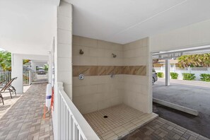 A covered outdoor shower area with tiled walls, a drain, and a lifebuoy. - Pool-view 1BR condo in Siesta Key with kitchen, WiFi, and heated pool. (Siesta Key)