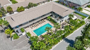 An aerial view of a hotel with a swimming pool surrounded by palm trees and lounge chairs. - Pool-view 1BR condo in Siesta Key with kitchen, WiFi, and heated pool. (Siesta Key)