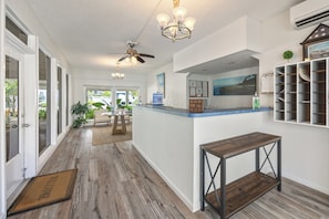 Ein Hotelkorridor mit Holzboden, einer Rezeption, einer Chandelüster und einem Deckenventilator.
