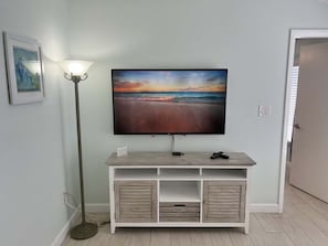 Ein Flachbildfernseher an einem hölzernen TV-Schrank, darüber ein Landschaftsbild.