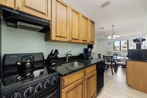 A kitchen with wooden cabinets, a black stove, and a sink. - Siesta Sands - Unit 206 (Siesta Key)