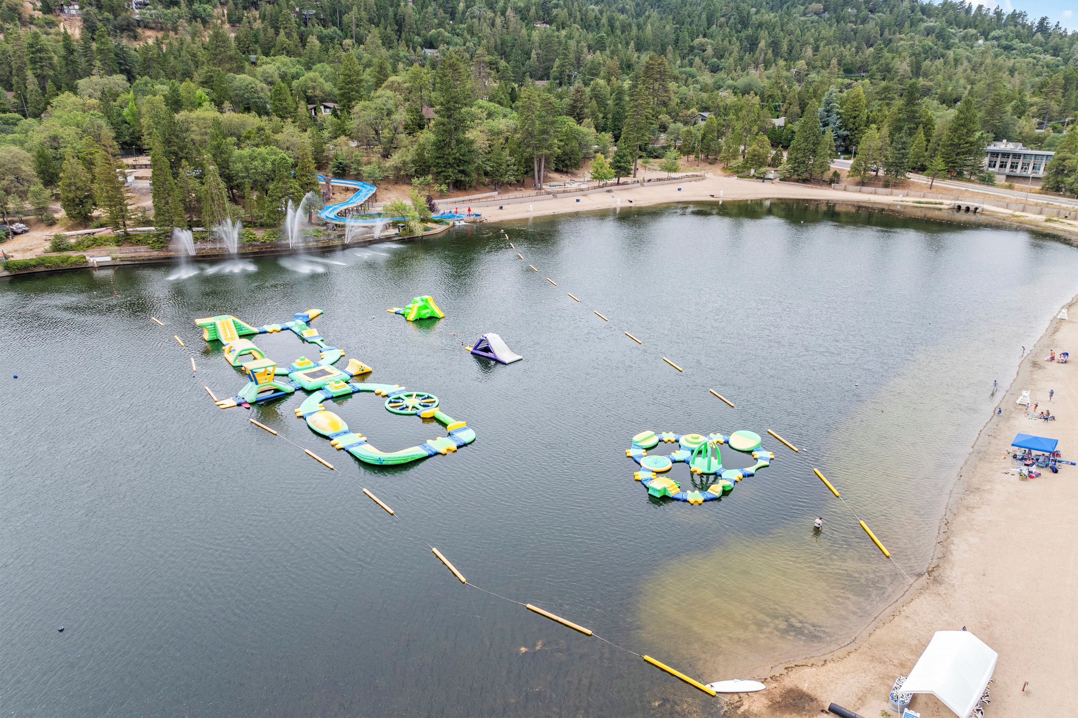 A lake with floating play structures and a sandy beach.