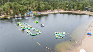 A lake with floating play structures and a sandy beach.