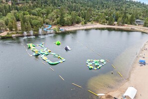 Un lago con estructuras flotantes para jugar y una playa de arena.