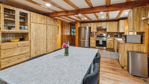 Une cuisine moderne dotée de meubles en bois, d’appareils électroménagers en acier inoxydable et d’un coin repas avec une table et des chaises.