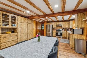 Una cocina moderna con armarios de madera, electrodomésticos de acero inoxidable y un comedor con mesa y sillas.