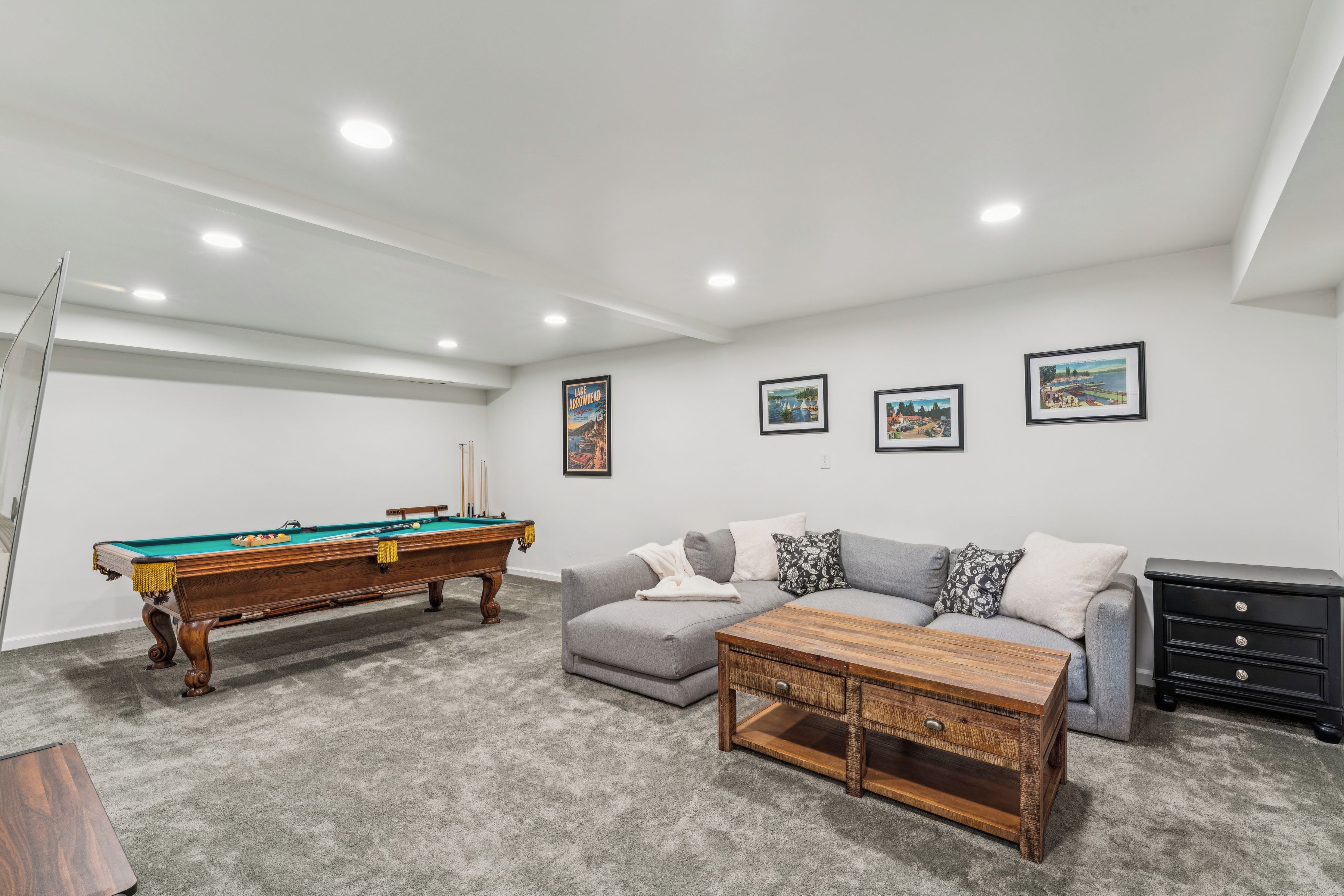 Une pièce avec une table de billard, un canapé gris et une table basse.