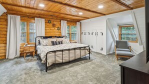 Une chambre située dans une cabane en rondins, avec un lit, une chaise, un bureau et une armoire.