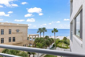 A balcony with a view of a beach, palm trees, and a pool. - Siesta Sands - Unit 508 (Siesta Key)