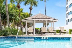 A pool area with lounge chairs and a gazebo, surrounded by palm trees. - Siesta Sands - Unit 508 (Siesta Key)