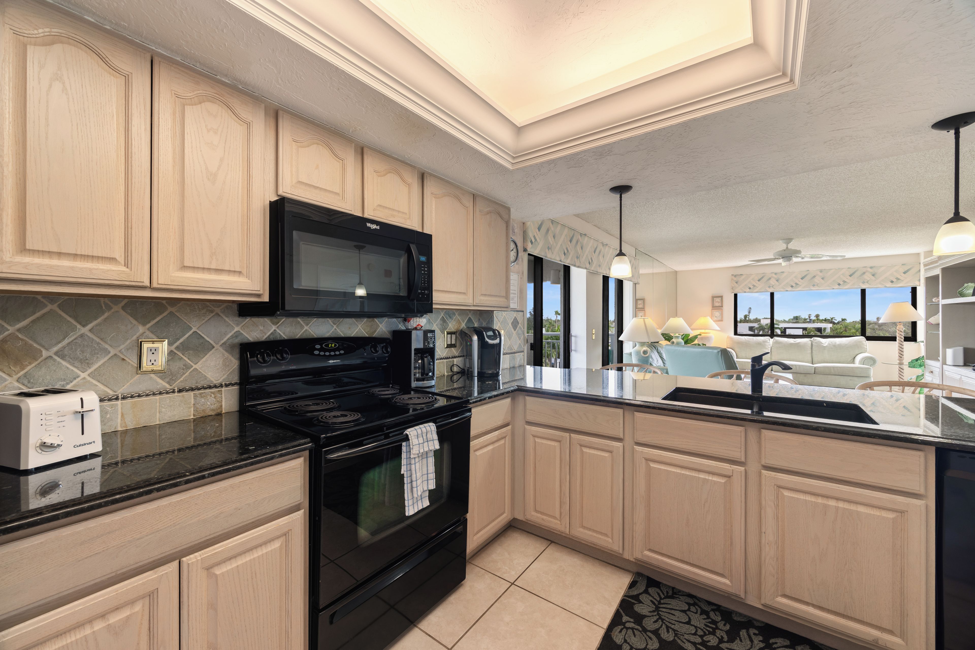 A modern kitchen with wooden cabinets, a black stove, a microwave, and a coffee maker.