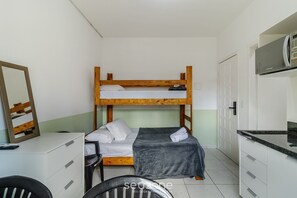 A bunk bed with a desk and chair, a mirror, and a microwave in a small room with white cabinets and a tiled floor. - Functional Loft in the Center of Floripa Flt0001 (Florianópolis)