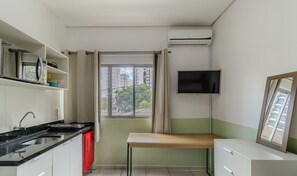 A compact kitchen with a microwave, stove, sink, and a small dining table. - Functional Loft in the Center of Floripa Flt0001 (Florianópolis)