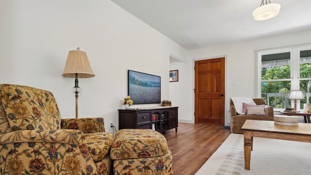 Una sala de estar con sofá, una mesa de centro, una lámpara, un televisor y una puerta de madera.