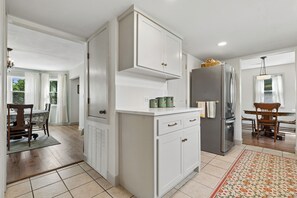 Eine moderne Küche mit weißen Schränken, einem Edelstahl-Kühlschrank und einem Essbereich mit einem Holztisch und Stühlen.