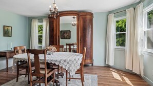 Un comedor con una mesa de madera, sillas, una araña y un espejo grande.