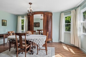 Ein Esszimmer mit Holztisch, Stühlen, einer Chandelieber und einem großen Spiegel.