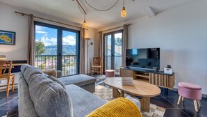 A modern living room with a sofa, a coffee table, a TV, and a view of the outdoors. - Ti Kaz Komela - Vue montagnes - Terrasse (Le Tampon)