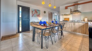 A modern kitchen with a dining area, featuring a wooden table, chairs, and pendant lighting. - Ti Kaz Komela - Vue montagnes - Terrasse (Le Tampon)
