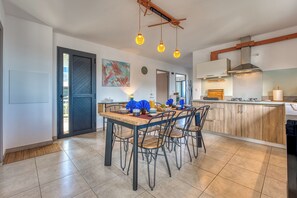 A modern kitchen with a dining area, featuring a wooden table, chairs, and pendant lighting. - Ti Kaz Komela - Vue montagnes - Terrasse (Le Tampon)