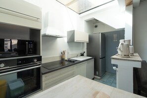 A compact kitchen with a microwave, oven, and refrigerator. - La Charmante - Centre-ville - Wifi (Le Mans)