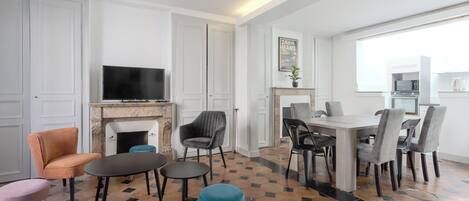 A modern living room with a fireplace, seating area, and a dining table with chairs.