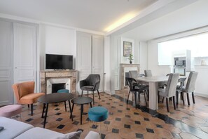 A modern living room with a fireplace, seating area, and a dining table with chairs. - La Charmante - Centre-ville - Wifi (Le Mans)