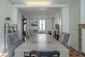 A dining area with a long table, chairs, a sofa, and a TV. - La Charmante - Centre-ville - Wifi (Le Mans)