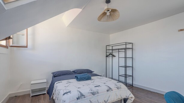 Quarto com cama, guarda-roupa, luminária pendente e janela.