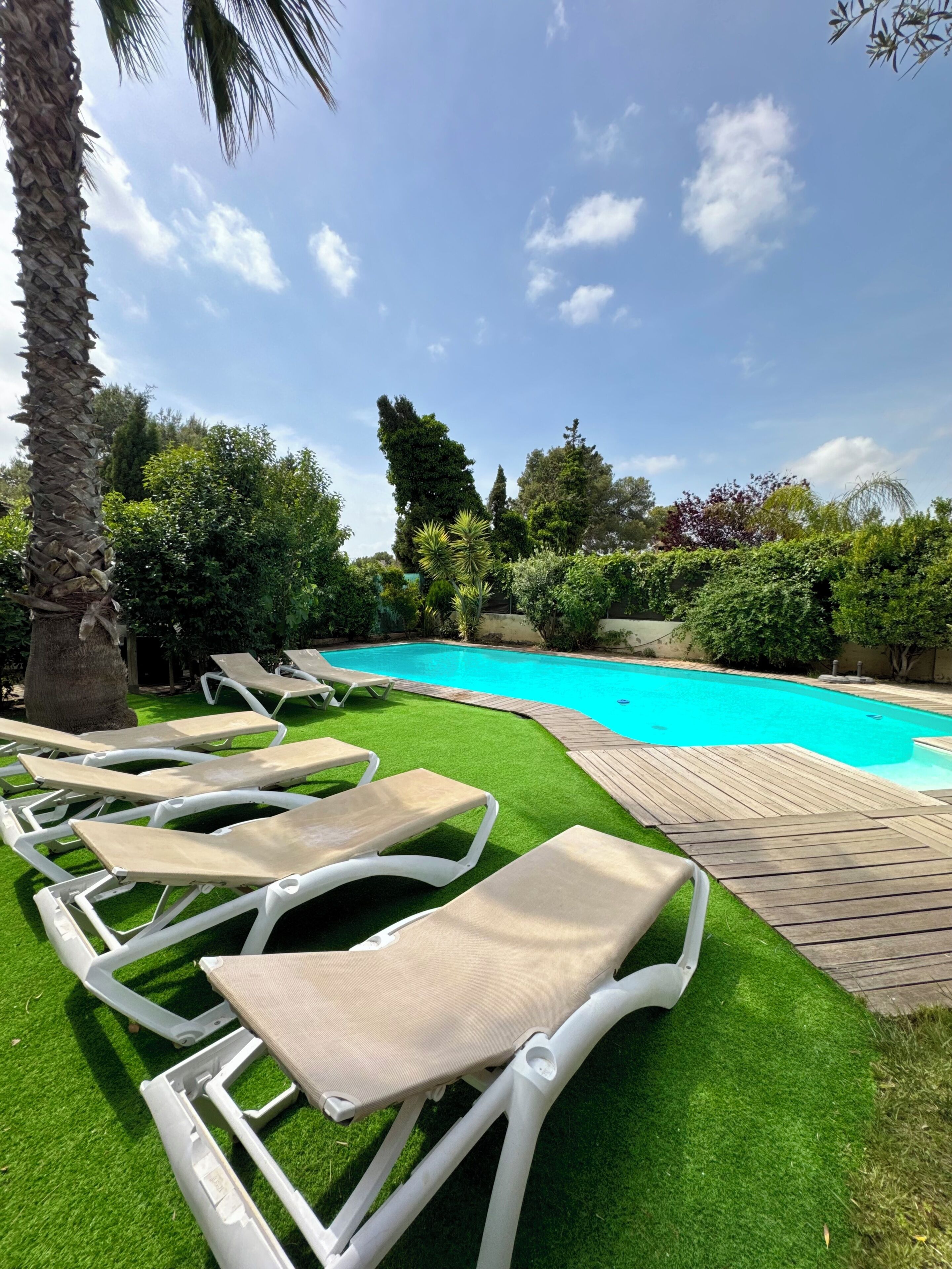 A swimming pool with lounge chairs and artificial grass.