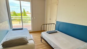Ein Zimmer mit zwei Betten, einem großen Fenster und Blick auf Grünfläche.