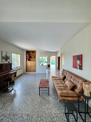 Un vaste espace de vie comprenant un canapé en cuir marron, un meuble en bois et une petite table.