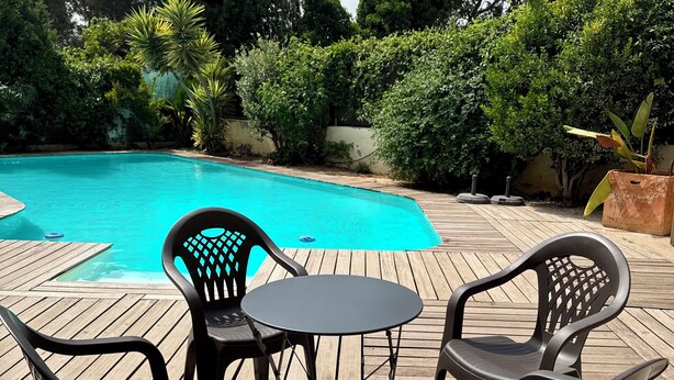Ein Poolbereich mit Holzterrasse, einem runden Tisch und vier Stühlen.
