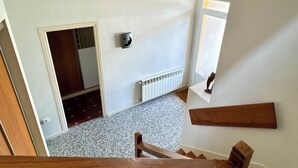 Eine Treppe mit Holzwangen führt zu einem Raum mit Heizkörper, Tür und Wandleuchte.