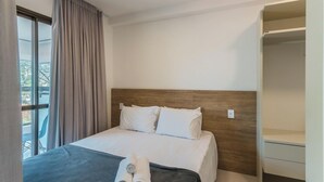A hotel room with a bed, a wooden headboard, a window with curtains, and a built-in closet. - Apt w/ Balcony 290 m From the Beach Hoa0308 (Salvador)