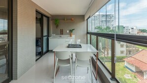 A modern kitchen with a white countertop, a hanging plant, and a view of the city through large windows. - Apt w/ Balcony 290 m From the Beach Hoa0308 (Salvador)