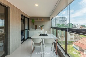 Una cocina moderna con encimera blanca, una planta colgante y vistas a la ciudad a través de amplios ventanales.
