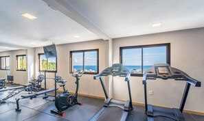 Uma academia com esteiras, bicicleta ergométrica e aparelhos de musculação.