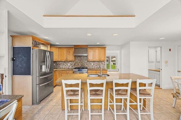 Una cocina moderna con una isla central, electrodomésticos de acero inoxidable y armarios de madera.