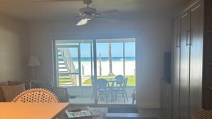 A room with a view of the beach, a ceiling fan, a dining table, and a sofa. - Gulf-front 1BR Siesta Key condo with king bed and sleeper sofa. (Siesta Key)
