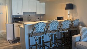 A compact kitchen with white cabinets, a microwave, a sink, and a ceiling fan. - Gulf-front 1BR Siesta Key condo with king bed and sleeper sofa. (Siesta Key)