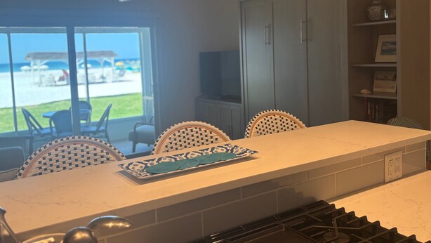 A kitchen with a dining area, a ceiling fan, and a view of the beach. - Gulf-front 1BR Siesta Key condo with king bed and sleeper sofa. (Siesta Key)