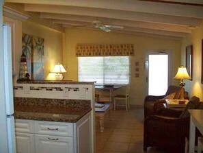A kitchen with a granite countertop, white cabinets, a dining area with a table and chairs, and a ceiling fan. - Gulf-front 1BR Siesta Key escape with king bed and sleeper sofa. (Siesta Key)