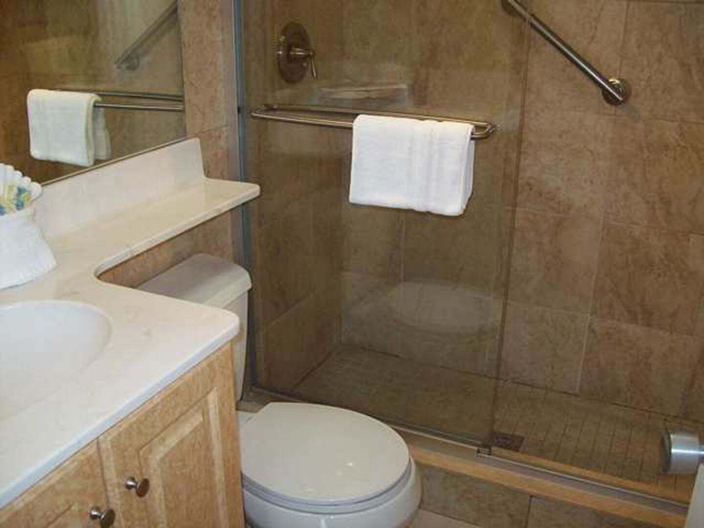 A bathroom with a toilet, sink, and shower area.