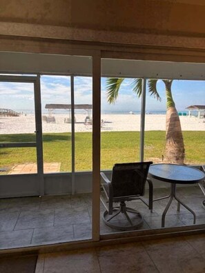 Ein Zimmer mit einer großen Glasdoor, die auf einen Strandblick führt, einem runden Tisch und einem Stuhl.