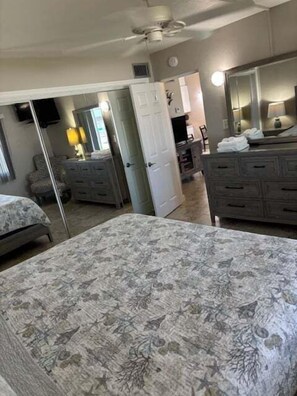 Ein Schlafzimmer mit Bett, Kommode und Spiegel.