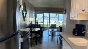 A kitchen with a refrigerator, stove, and sink, with a view of the outdoors. - SR-12A Gulf Front 1/1 (Siesta Key)