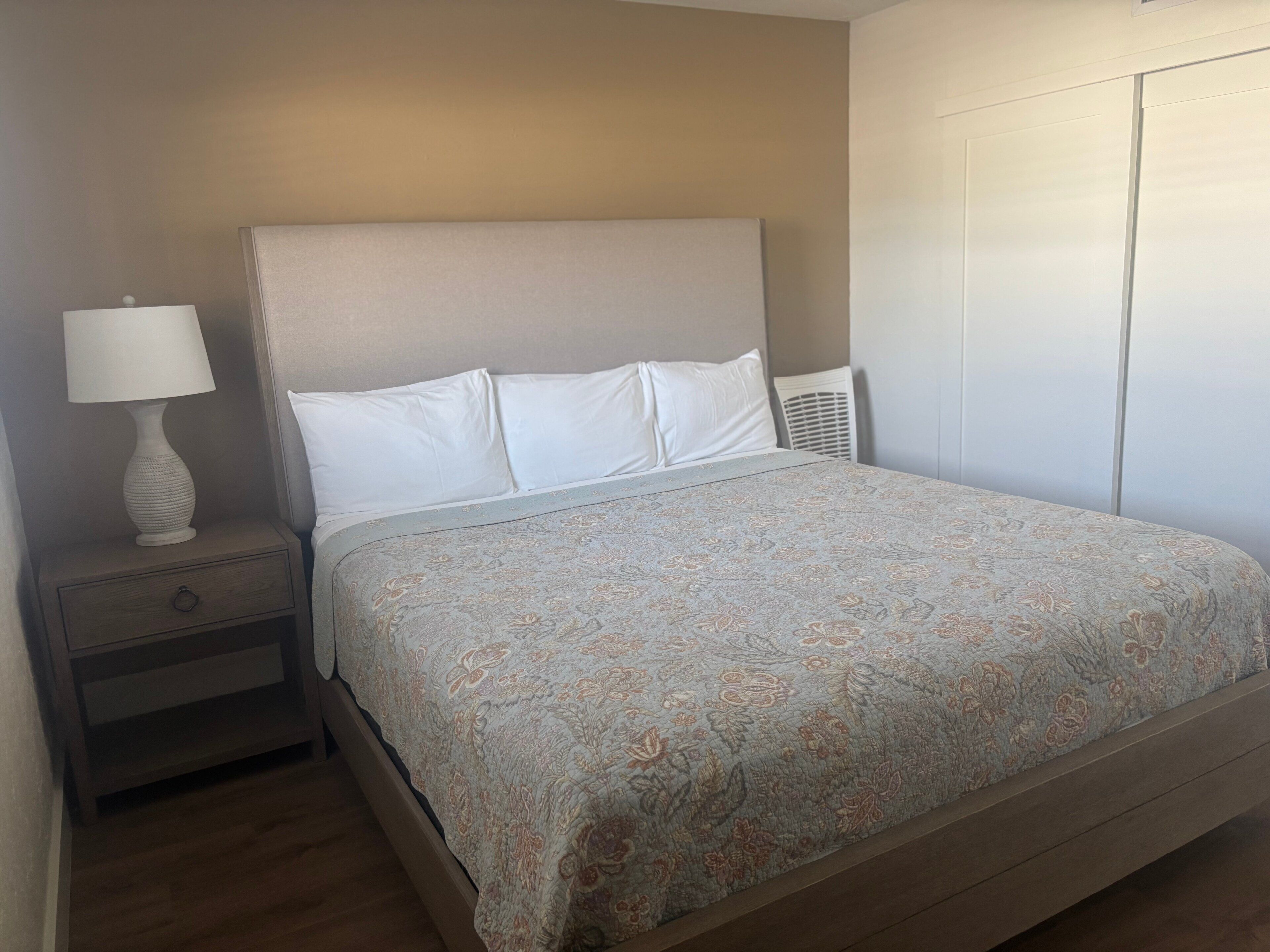 Ein Schlafzimmer mit einem Bett, einem Nachttisch, einer Lampe und einem Kleiderschrank.