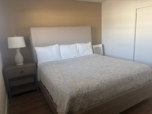 A bedroom with a bed, a nightstand, a lamp, and a wardrobe. - SR-15 Ground Floor Gulf Front (Siesta Key)