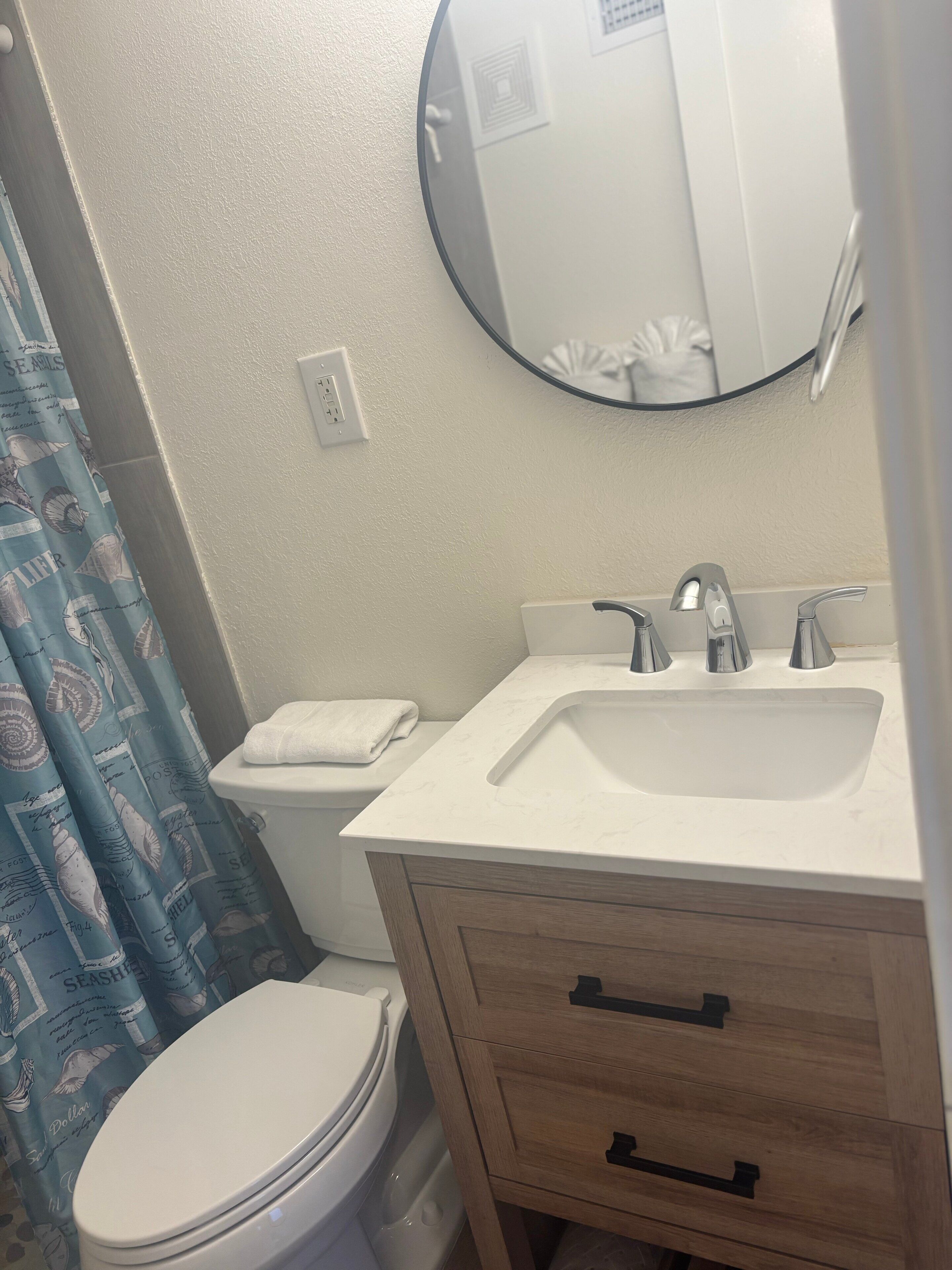 Un baño con inodoro, lavamanos, espejo y un armario de madera.